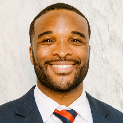 A man smiles as he poses for a headshot.